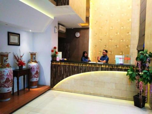 dos personas sentadas en un mostrador en un restaurante en Hotel Parma Pekanbaru en Pekanbaru