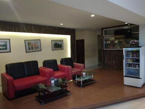 una sala de estar con sillas rojas y un estante para libros. en Hotel Parma Pekanbaru, en Pekanbaru