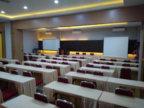 Hotel Parma Pekanbaru في بيكانبارو: قاعة محاضرات مع طاولات وكراسي وطاولة بيضاء