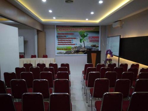 una sala de conferencias con sillas rojas y una pantalla en Hotel Parma Pekanbaru en Pekanbaru