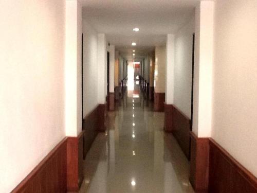 um corredor vazio com um longo corredor com paredes brancas em PC Palace Hotel em Sakon Nakhon