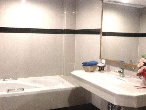 y baño con lavabo, bañera y espejo. en PC Palace Hotel en Sakon Nakhon
