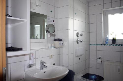 Ferienwohnung Mars FN في فريدريشسهافن: حمام أبيض مع حوض ومرآة