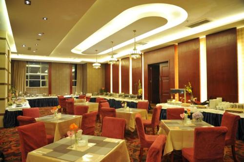 ein Restaurant mit Tischen und Stühlen in einem Zimmer in der Unterkunft Kunming Zhong Huang Hotel in Kunming