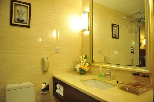 ein Badezimmer mit einem Waschbecken und einem großen Spiegel in der Unterkunft Kunming Zhong Huang Hotel in Kunming