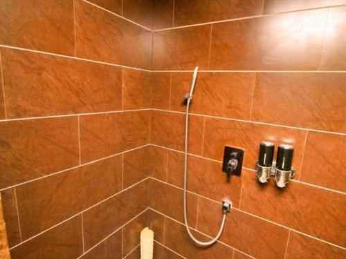 a brown tiled shower with a hose in a bathroom at Xian I-OPAL Hotel in Chang'an