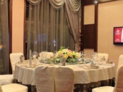 een eetkamer met een tafel met witte tafellakens en bloemen bij Guangyuan Hotel Gutian Fujian 