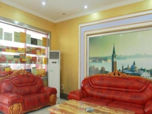 two red leather couches in a room with a large window at Kunlun Leju Business Hotel Kaifeng Gulou in Kaifeng