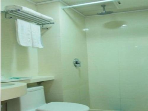 a white bathroom with a shower and a toilet at Kunlun Leju Business Hotel Kaifeng Gulou in Kaifeng
