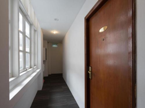 a hallway with a wooden door and a window at Penta Hotel in Singapore