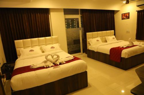 two beds in a hotel room with towels on them at ANNAI RESIDENCY in Vellore