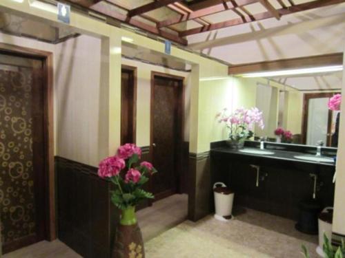 baño con lavabo y jarrón de flores en Chodkamol Place 57, en Nakhon Si Thammarat