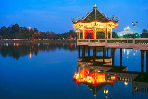 a pagoda in the middle of a lake at night at Tai Asean House in Udon Thani