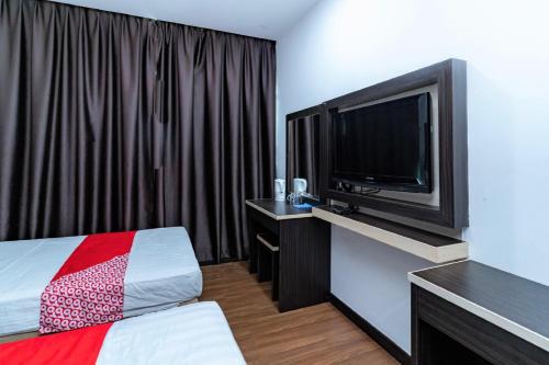 a hotel room with a bed and a flat screen tv at OYO 90375 Reggae Inn in Bintulu