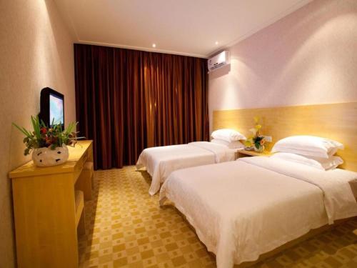 a hotel room with three beds and a television at Nanning Hawks Holiday Hotel in Nanning