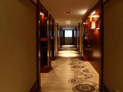 einen Flur eines Hotels mit einem langen Gang mit Teppich in der Unterkunft Quanzhou Jinjiang Hollyston Hotel in Jinjiang