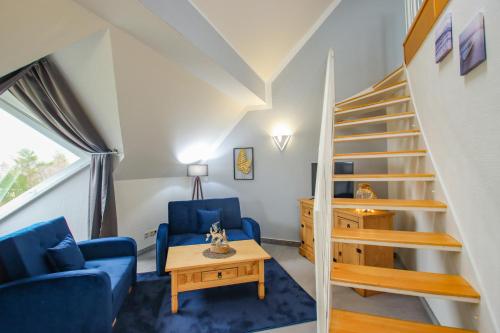 a living room with stairs and blue chairs and a table at Inselhotel kleiner Bodden in Buschvitz