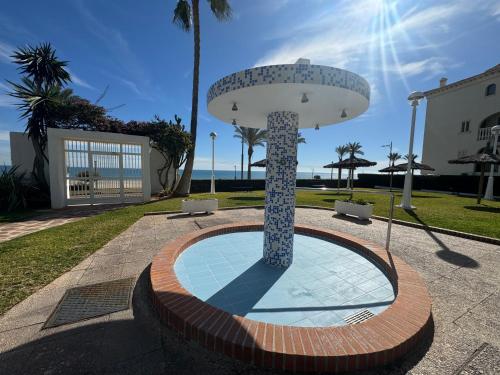 a fountain in a park with two chairs and the ocean at Apartamento Muchavista Primera Línea de Playa By El Conserje in El Campello