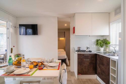 a kitchen with white cabinets and a table with fruit on it at La Risacca Family Camping Village in Porto SantʼElpidio