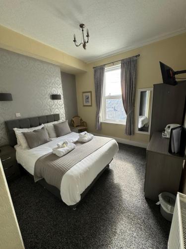 ein Schlafzimmer mit einem großen Bett und einem Fenster in der Unterkunft Winchmore Hotel in Llandudno