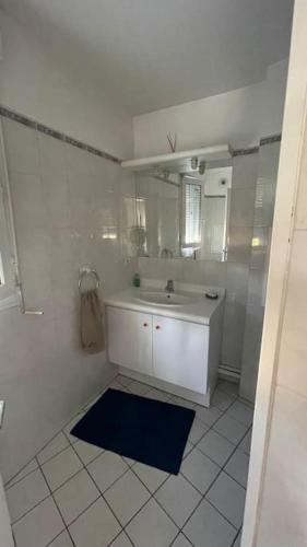 une salle de bain blanche avec un lavabo et un miroir dans l'établissement Beau studio spacieux et calme dans résidence de standing, à Boulogne-Billancourt