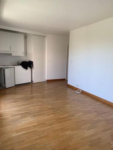 une chambre vide avec une cuisine et du parquet dans l'établissement Beau studio spacieux et calme dans résidence de standing, à Boulogne-Billancourt