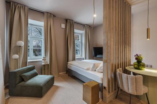 1 dormitorio con cama, silla y escritorio en kalm stay - a design Aparthotel, en Múnich