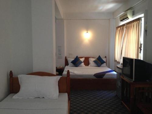 a hotel room with two beds and a television at Mya See Sein Hotel in Myeik