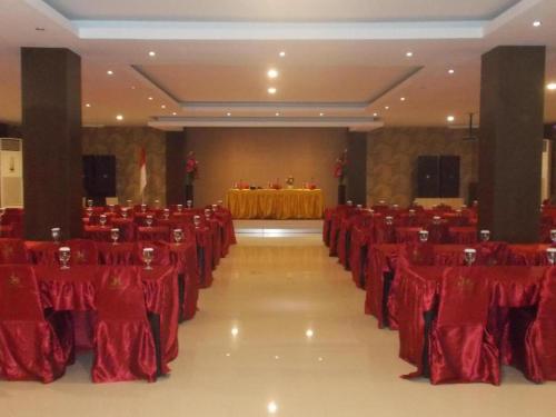 John's Hotel في Maulafa: قاعة احتفالات بكراسي حمراء وطاولة