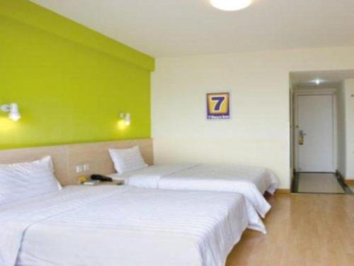 2 camas en una habitación con una pared verde en 7 Days Inn Luoyang Wangcheng Park Metro Station en Luoyang