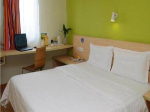 1 dormitorio con cama blanca y pared verde en 7 Days Inn Luoyang Wangcheng Park Metro Station en Luoyang