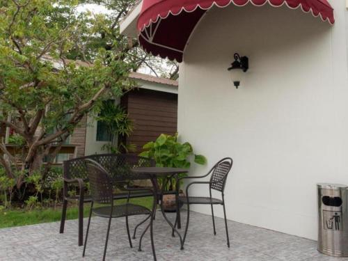 a table with chairs and an umbrella on a patio at Baan Kula Mahasarakam in Maha Sarakham