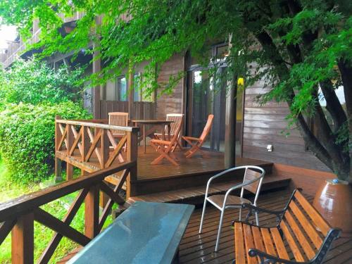 a deck with two chairs and a table and chairs at Kirishima Onsen Ryokojin Sanso in Kirishima