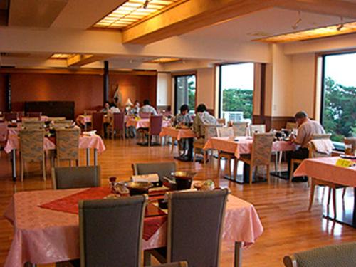 um restaurante com mesas e pessoas sentadas às mesas em Kirishima Onsen Ryokojin Sanso em Kirishima