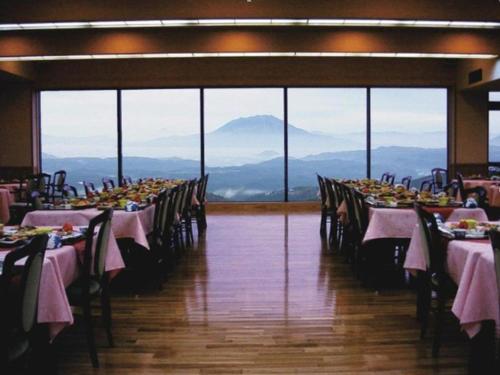 a dining room with tables with mountains in the background at Kirishima Onsen Ryokojin Sanso in Kirishima