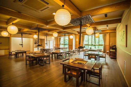 una sala da pranzo con tavoli, sedie e luci di Hotel Hikyounoyu a Itchū