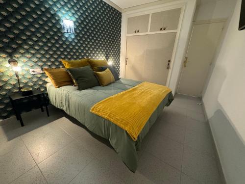 a bedroom with a bed with a yellow blanket on it at Apartamento Muchavista Primera Línea de Playa By El Conserje in El Campello