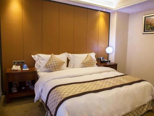 a bedroom with a large bed with a large headboard at Auspicious Hotel in Zhongshan