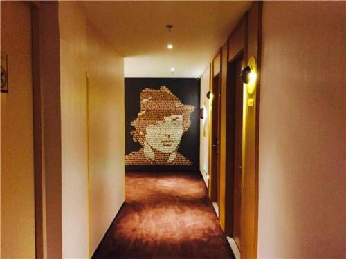 a hallway with a painting of a face on the wall at IU Hotel Shanghai Jiaotong University Jiangchuan Road Metro Station 