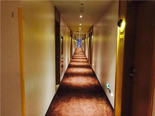an empty hallway in a building with a long corridor at IU Hotel Shanghai Jiaotong University Jiangchuan Road Metro Station 