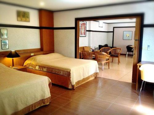 Numsin Hotel في Ban Rong Chang: غرفة فندقية بسريرين وغرفة طعام