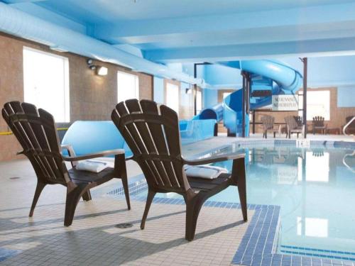 Comfort Inn & Suites في Virden: كرسيين وطاولة بجانب مسبح