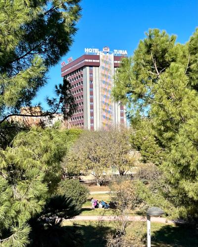 a hilton hotel seen through the trees in a park at Turia Valencia in Valencia