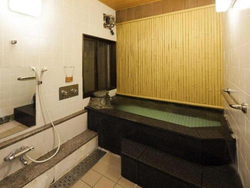 a bathroom with a tub and a shower with a mirror at Yudaonsen Ubl Hotel Matsumasa in Nakaichi
