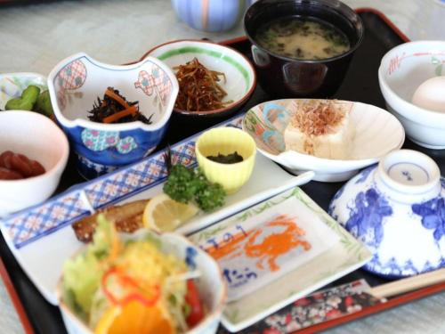 a tray of food with bowls and plates of food at Tara Kanko Hotel in Kamenoura