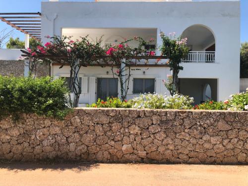 a house with flowers on a stone wall at Villa Alexandros in Porto Heli