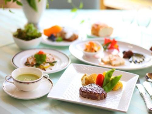 una mesa con platos de comida y una taza de té en Takato Sakura Hotel en Ina