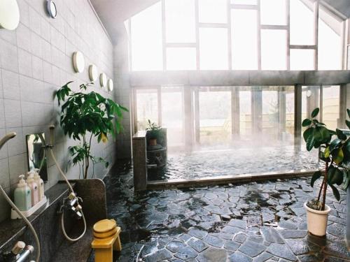 un baño con una piscina de agua con plantas. en Takato Sakura Hotel en Ina