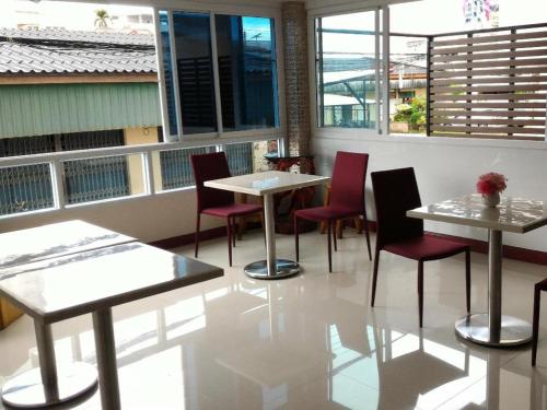 un restaurante con mesas, sillas y ventanas en V-House Hotel, en Trang