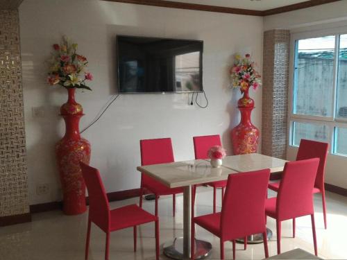 a dining room with a table and red chairs at V-House Hotel in Trang